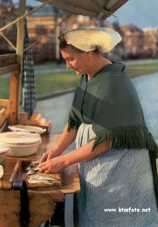 'n 
Visservrou staan en maak die 
haringe skoon op die 'visafslag'; die plek waar die vis aan land gebring en verhandel word